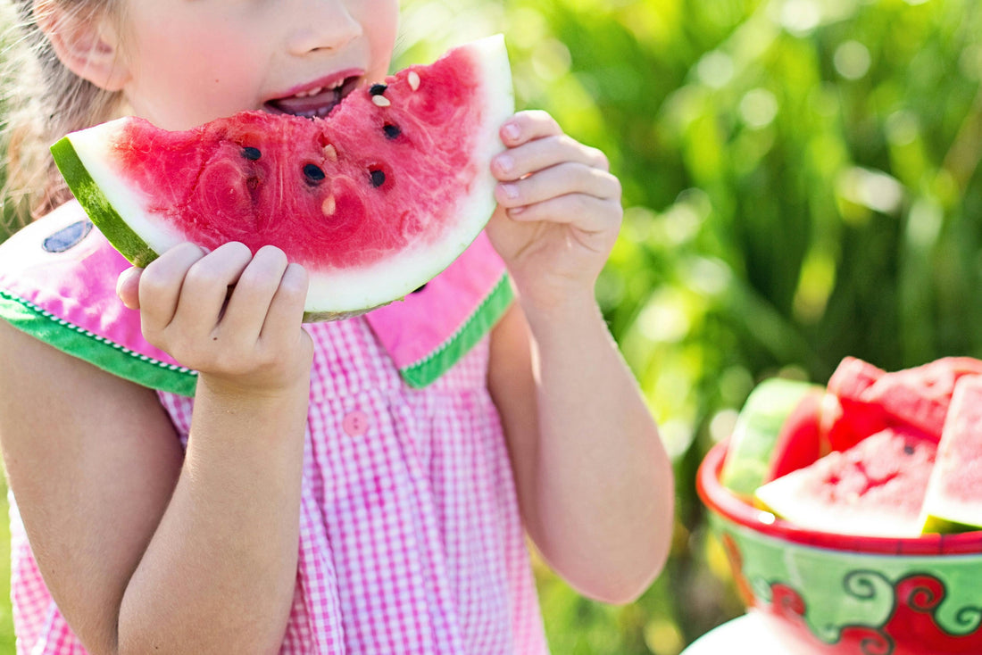 Mädchen in sommerlicher Kleidung isst eine Wassermelone